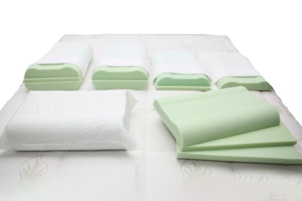Almohada viscoelástica Multitalla y toallas plegadas sobre una cama blanca.