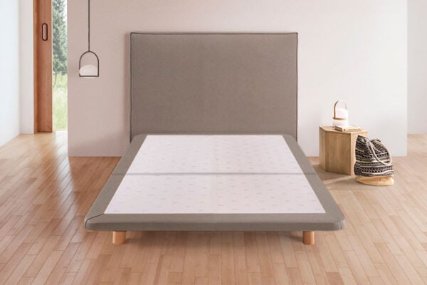 Dormitorio minimalista con base de cama KHAMA tapizada Napua deshecha y mesita de noche sencilla.