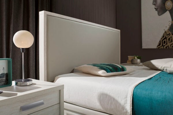 Dormitorio moderno con tonos neutros, con mesita de noche Cabecero modelo Kiara Soft con lámpara y obras de arte en la pared.