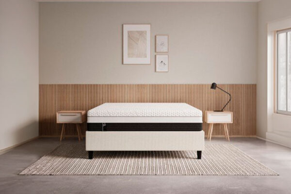 Un dormitorio minimalista con un moderno Colchón EMMA Diamond Degree Foam, dos mesas auxiliares y una lámpara de pie, con colores neutros y una decoración sencilla.