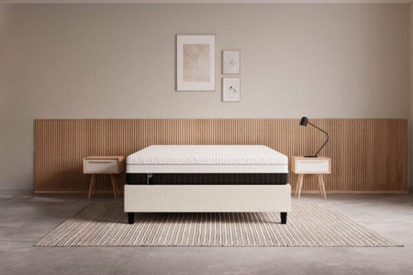 Un dormitorio moderno con un diseño minimalista que cuenta con un Colchón EMMA Diamond Degree Hybrid, dos mesas auxiliares, una obra de arte de pared y una lámpara de pie.
