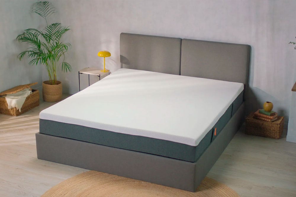 Un dormitorio moderno con un Colchón EMMA Original tamaño king con cabecera gris, colchón blanco y muebles minimalistas.