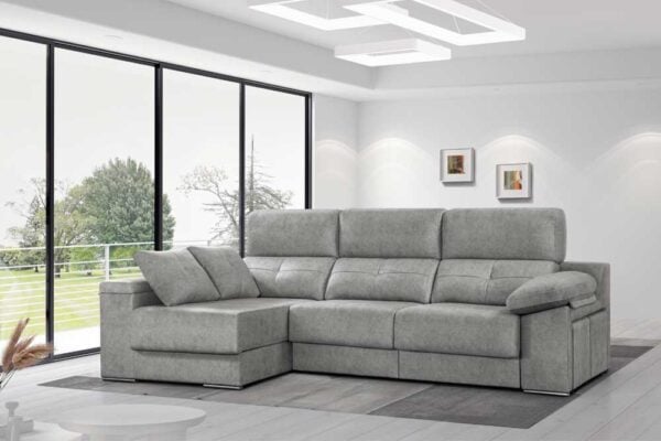 Moderno sofá seccional gris con chaiselongue modelo Kimberly EXPRESS en una luminosa sala de estar con grandes ventanales con vistas a la vegetación.