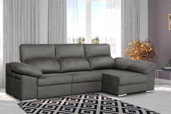 Un sofá seccional Chaiselongue modelo Spencer EXPRESS gris en una sala de estar moderna con una alfombra estampada y cortinas claras.