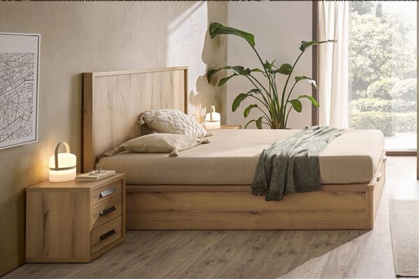 Interior de dormitorio moderno con cama de madera y mesita de noche modelo Kiara, con ropa de cama neutra, plantas verdes y luz natural.