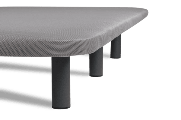 Esquina de una mesa moderna con superficie texturizada y patas cilíndricas sobre fondo negro.
